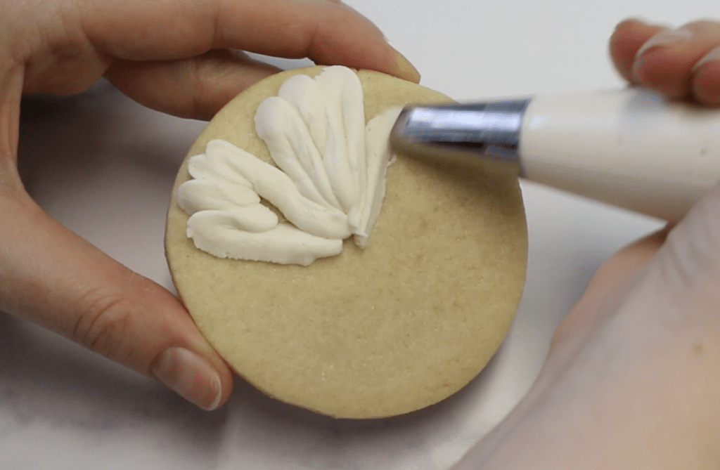 Continue piping ruffled petals and rotate the cookie 