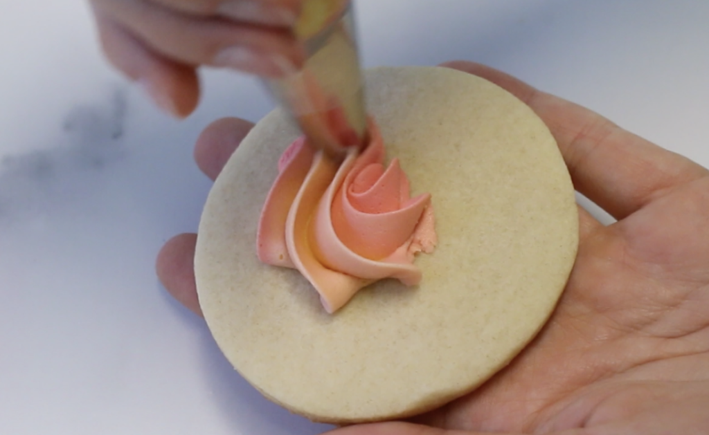 With the rosette tip, start the swirl in the center of the cookie